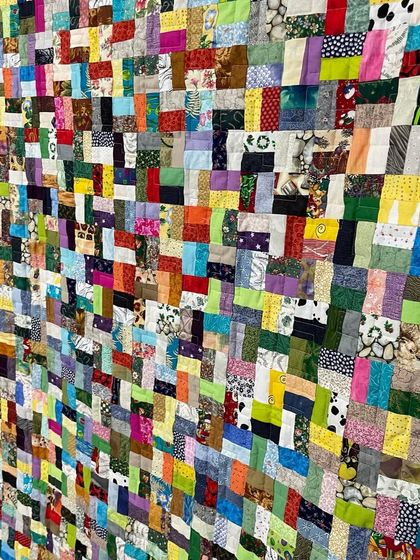 An angled view of the dense scrappy quilt, highlighting its texture and the sheer number of fabrics used.