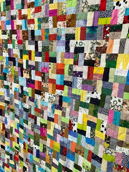 An angled view of the dense scrappy quilt, highlighting its texture and the sheer number of fabrics used.