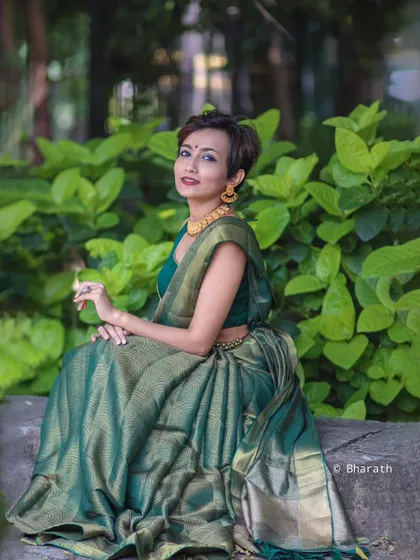 A wider shot of the model in the green saree, seated in a park. This image highlights how traditional wear can be styled for a modern, everyday context.