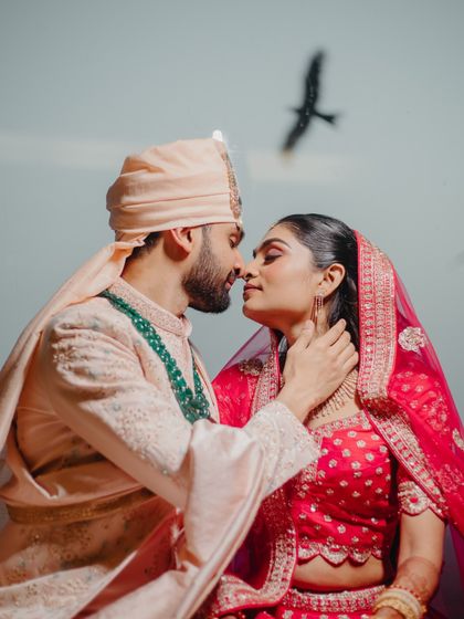 A stunning couple portrait with a bird in flight, capturing a perfect, serendipitous moment. The near-kiss pose is full of anticipation.