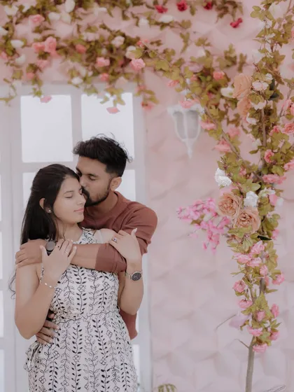 A tender moment against a romantic floral backdrop. The soft pink tones and the couple's gentle embrace create a dreamy and affectionate pre-wedding portrait.