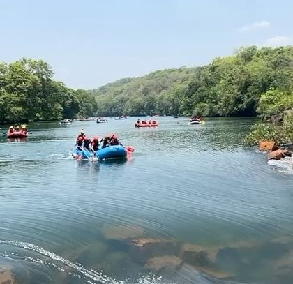 A wide shot of the river, with rafts and kayaks enjoying the vast, open water under a clear sky.