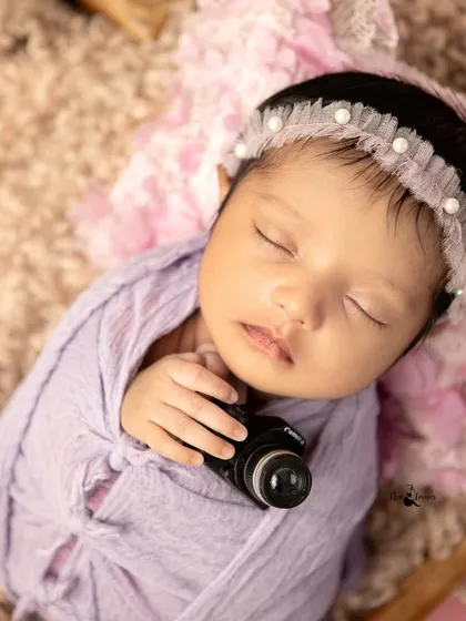A future photographer in the making! This newborn holds a miniature camera, a playful and unique prop that adds a personal touch to the session.