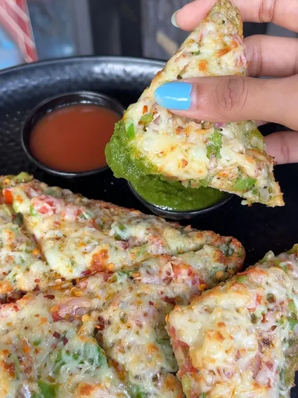 Dipping a piece of my Open Cheese Chilli Toast into our green chutney. The combination of spicy, cheesy, and tangy flavours is amazing.