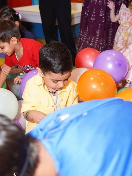 A child playing amongst a sea of colorful balloons in the play area. Simple joys and big smiles are what we aim to create every day.