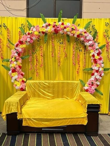 A unique take on the Haldi backdrop, this design features a full floral arch made of yellow, pink, and white flowers set against a simple yellow curtain. This is perfect for the main seating area of the bride or groom.