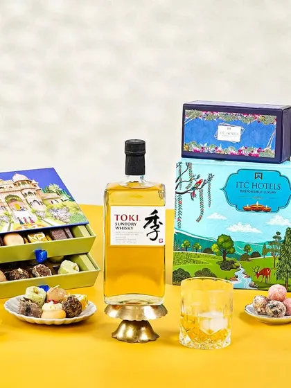 A premium Diwali gift set with Toki Suntory whisky and artisanal Indian sweets from ITC Hotels. The vibrant, illustrative packaging and clean styling create a luxurious and modern festive look.