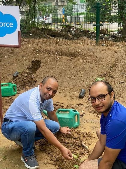 Two smiling volunteers from Salesforce plant a native sapling at Aravali Creek. Their team planted vital species like Bistendu, Gangeti, and Adusa to support local wildlife.