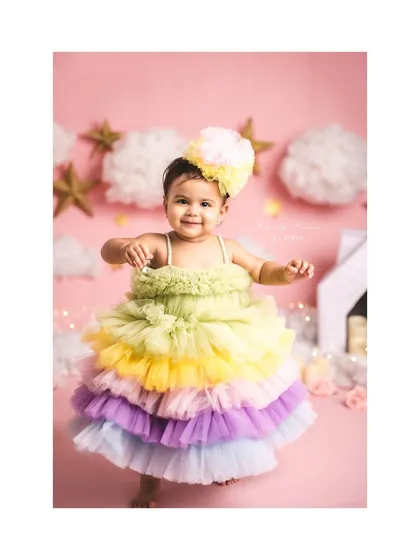 A beautiful portrait of a one-year-old girl in a rainbow dress, surrounded by stars and clouds.