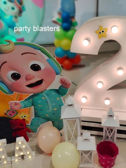 A close-up of the light-up number '2' next to a JJ cutout from Cocomelon. These large, illuminated numbers are a popular add-on for milestone birthdays.