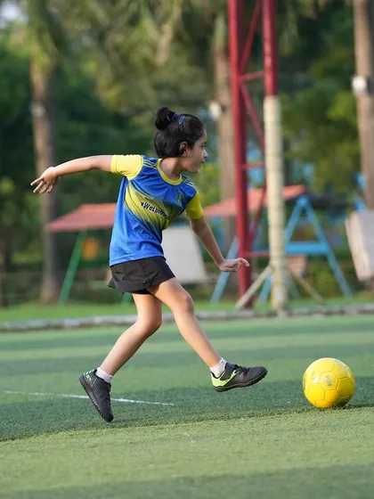 A young girl with a focused expression strikes a yellow ball during a training session. This simple, beautiful shot captures a player who has fallen in love with the game.
