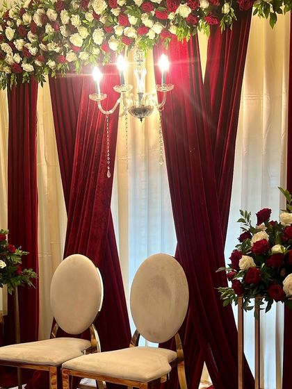 A close-up of this intimate Baat Pakki ceremony decor. The warm glow of the chandelier against the rich red velvet and classic white and red roses creates a feeling of timeless elegance.