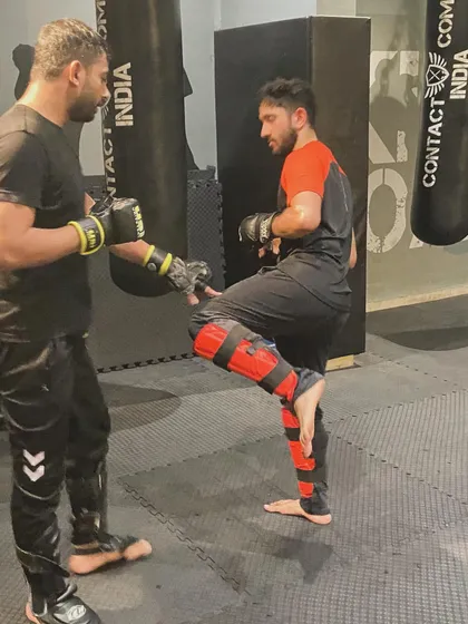 An instructor works one-on-one with a student, correcting his kicking technique. This personalized feedback is crucial for developing proper form and maximizing power.