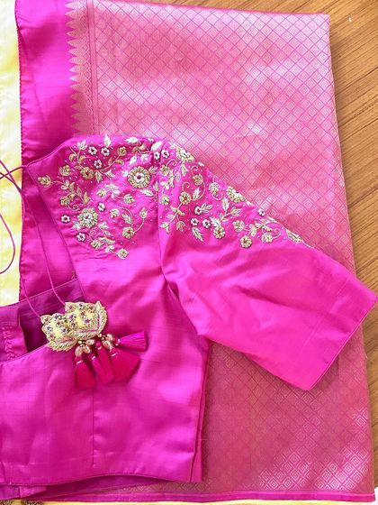 A pink raw silk blouse with minimal yet elegant embroidery details on the shoulder and a beautiful tassel tie-up.