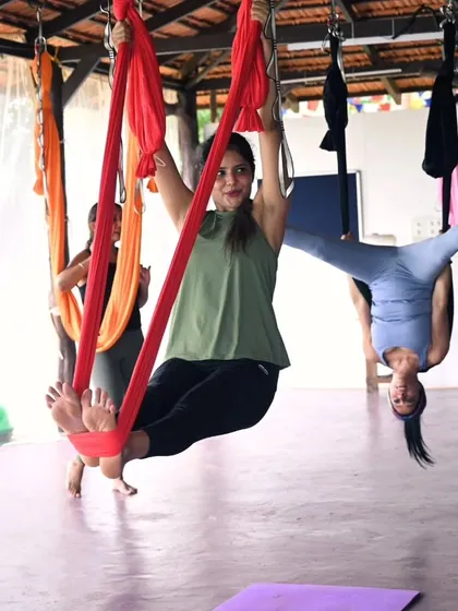 A student enjoying a playful swing in the aerial hammock. These sessions are as much about finding your inner child as they are about building strength and flexibility.