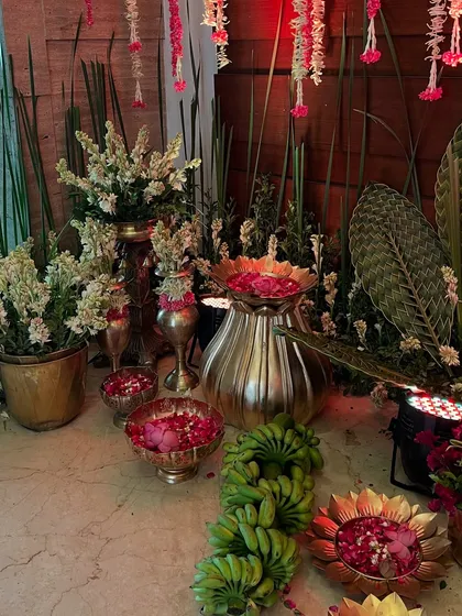 An assortment of brass urlis and pots filled with tuberoses and rose petals, creating a fragrant and devotional corner.
