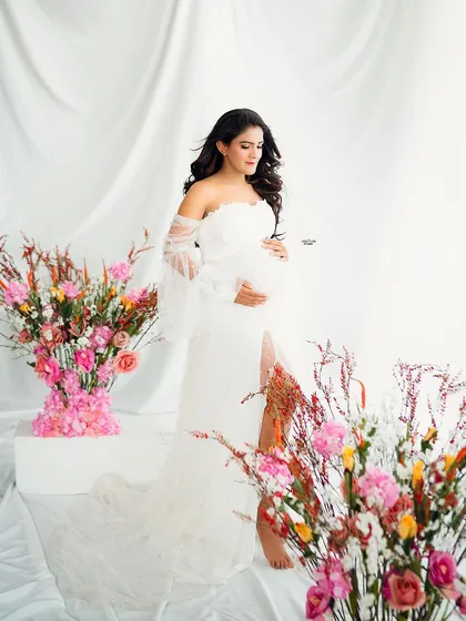 Beauty in serenity. This mamma looks absolutely angelic in a white gown, surrounded by a stunning arrangement of colorful flowers.