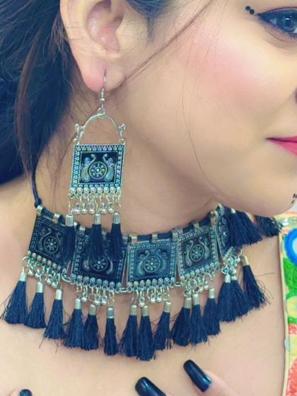 A model wearing the black tassel choker with matching earrings. The intricate design on the silver pieces is clearly visible.