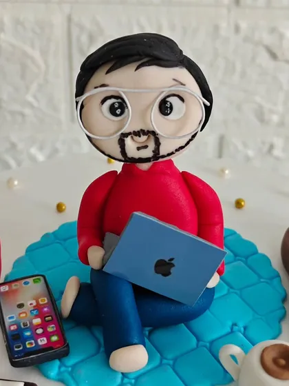 The star of the hobby cake: a detailed fondant figurine of the birthday boy, complete with glasses, a beard, and his laptop.