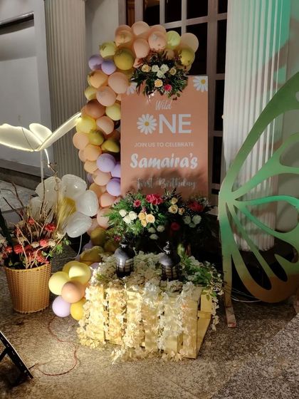 A whimsical welcome corner with a custom sign, light-up butterfly wing, and floral arrangements.