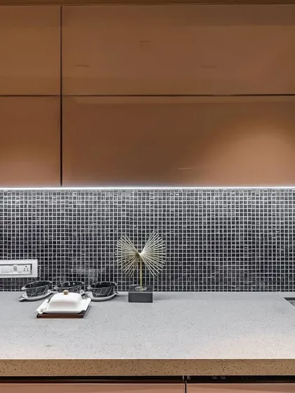 A close-up of the countertop in a parallel acrylic kitchen, showing a mosaic tile backsplash.