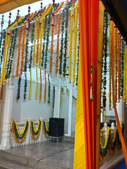 A view of the walkway at a home wedding function. We used hanging garlands of fresh flowers and colorful drapes to create a festive passage for guests, leading into the main event area.