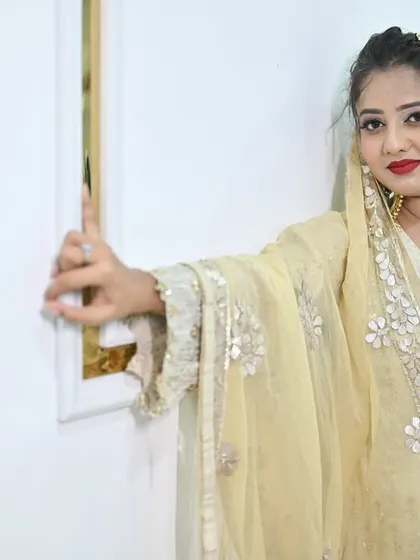 A model posing gracefully in the ivory sharara set, highlighting the delicate floral embroidery on the sheer dupatta.