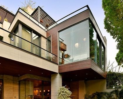 The facade of this modern Gurgaon home is a composition of intersecting planes, materials, and voids. The design uses balconies, large windows, and recessed volumes to create a dynamic and visually interesting exterior that still feels warm and residential.
