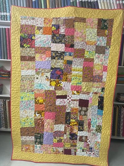 A scrappy patchwork quilt with a bright yellow border.