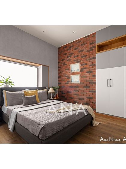 A guest room in Apartment 704, designed with a minimal color tone. A raw brick accent wall adds texture and warmth, contrasting with the sleek, modern wardrobe and cemento-textured walls for a balanced aesthetic.