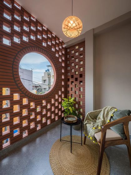 This cozy balcony corner is shielded by a beautiful brick jali wall. The design provides privacy and ventilation, creating a perfect, breezy spot to relax with a book.