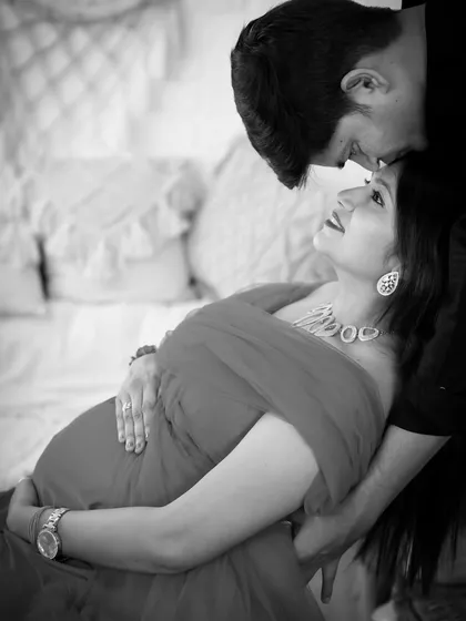 A black and white version of a tender moment. The partner kisses the mom-to-be's forehead, creating a classic and emotional image.