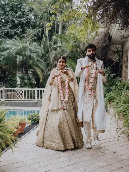 A stylish portrait of the couple walking through a lush garden path after their ceremony.