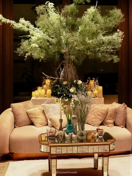 A 'Winter Wonderland' themed cocktail engagement. This lounge area features a tree covered in baby's breath, plush velvet seating, and a mirrored coffee table, all bathed in soft candlelight to create a magical, snow-dusted atmosphere.