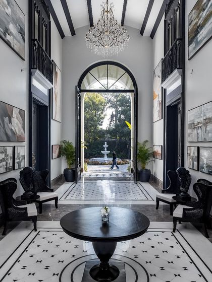 The grand foyer of the House of Verandahs is a study in symmetry and scale. We used contrasting black and white marble and a soaring ceiling to create a powerful axial view that connects the entrance directly to the heart of the home and the landscape.