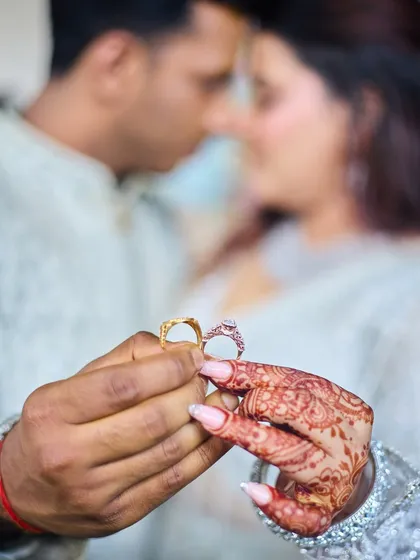 This close-up shot focuses on the engagement rings, a powerful symbol of the couple's promise. I use a shallow depth of field to draw attention to the rings and the bride's henna, with the couple sharing an intimate moment in the background.