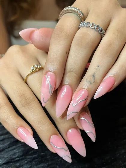 A full view of the long, dramatic pink and chrome stiletto nails.