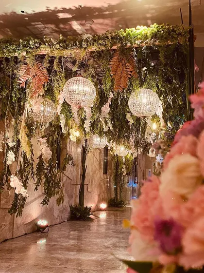 A wide shot of the enchanted forest decor, with hanging crystal balls and lush greenery creating a dramatic and immersive entryway for an engagement party.
