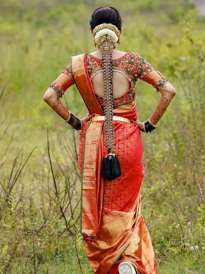 A classic muhurtham look featuring a bright red lip and defined eyes. The traditional matha patti and heavy gold jewellery are perfectly balanced with the makeup, and the bridal braid with fresh flowers is a timeless choice.