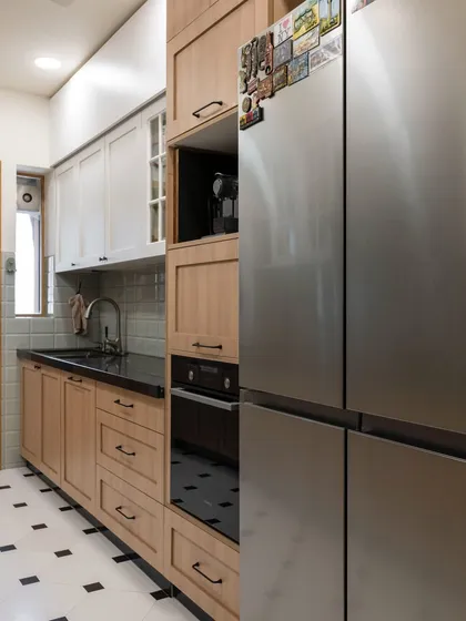 The full-height cabinetry next to the refrigerator maximizes storage and creates a clean, built-in look. The mix of wood and white cabinets adds depth and character to the design.