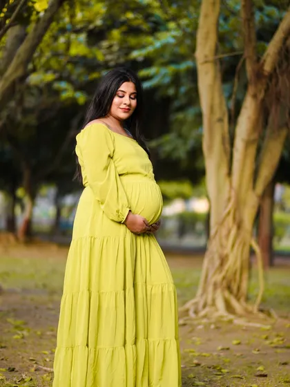 A peaceful solo portrait of the mom to be, cradling her bump in a lovely tiered gown. The natural setting adds a sense of calm and tranquility to the photograph.