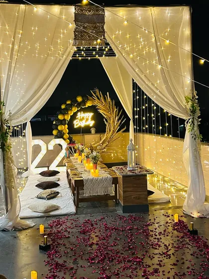 An elegant and intimate rooftop birthday celebration for a 22nd birthday. This cabana setup features low seating, beautiful fairy lights, candlelit decor, and a stylish balloon arrangement with a neon sign, creating a chic and memorable atmosphere.