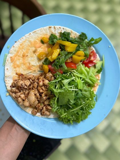 A deconstructed chicken wrap on a whole grain tortilla, loaded with fresh greens, bell peppers, and seasoned chicken. A perfect DIY high-protein meal.
