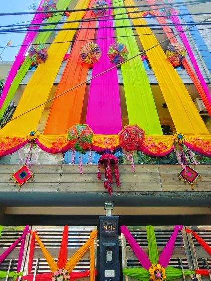A beautiful house front combining multi-coloured drapes, Rajasthani umbrellas, and star-shaped gate decorations for a complete festive look.