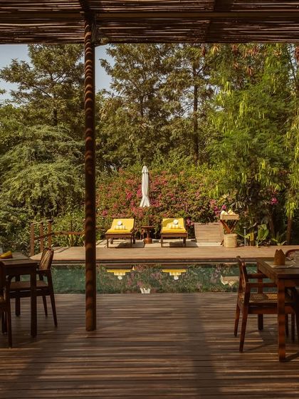 The view from the covered pavilion, looking out over the dining tables to the sun-drenched pool and loungers.