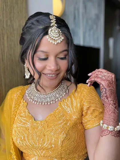 A close-up of the yellow outfit look, featuring a traditional maang tikka and soft, pretty makeup.
