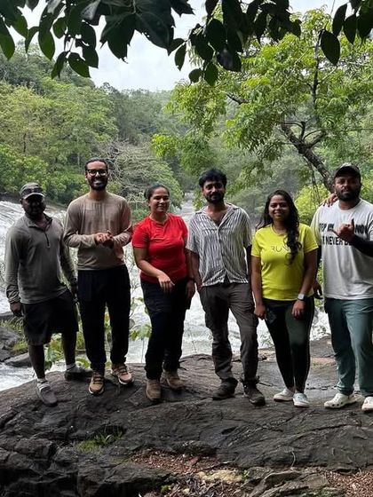 A group of friends posing on a large rock by a river, a great memory from their trek.