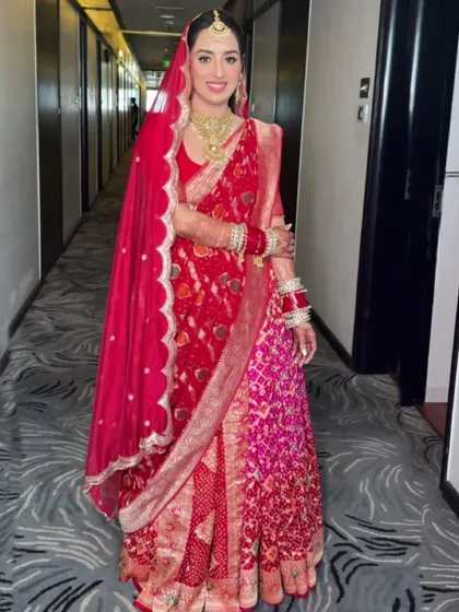 This bride's happiness is infectious. I draped her in a traditional two-saree style, blending red and pink bandhani to create a unique and vibrant bridal look for her Grah Pravesh.