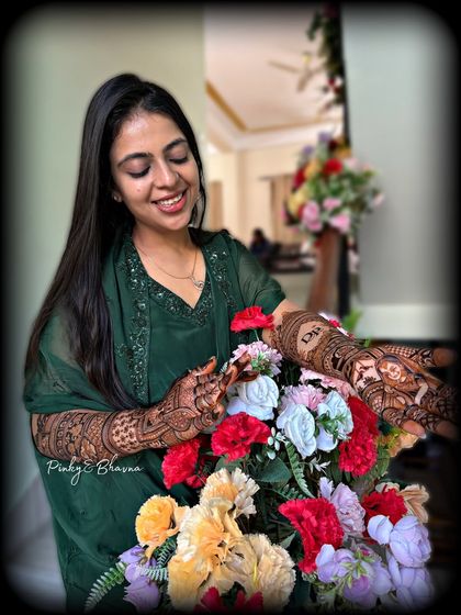 A candid moment with a smiling bride and her beautiful mehndi. The design includes a custom portrait and the couple's initials, making it a truly personal piece of art for her wedding in Siliguri.