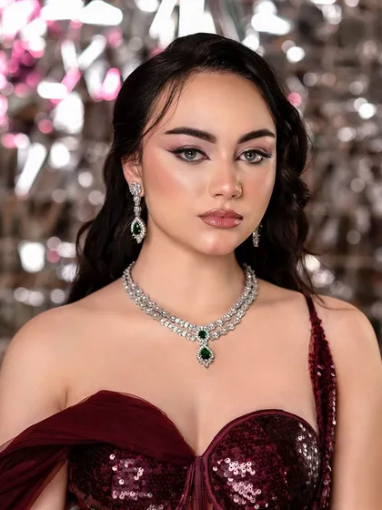A beautiful portrait showcasing a modern reception or party look. The shimmering background and elegant jewelry create a sophisticated and celebratory mood.